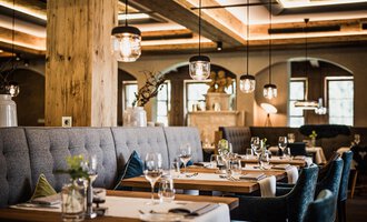 A stylish restaurant with elegant tables and comfortable seating. The cozy atmosphere is enhanced by soft lighting and natural materials. | © Verwöhn- & Wellnesshotel Walserhof| Aileen Melucci