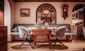 An elegant dining room with a large wooden table and comfortable seating. It has a cozy atmosphere with decorative elements and soft lighting. | © Hotel Birkenhöhe | Sascha Gast