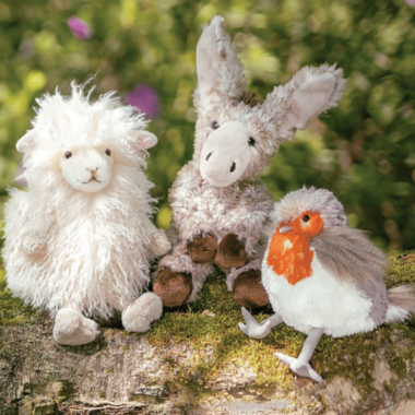 Three cute plush toys are sitting on a tree trunk: a sheep, a donkey, and a bird. They look friendly and are surrounded by a natural environment. | © Rohn - Kinder, Trends und mehr | Wrendale