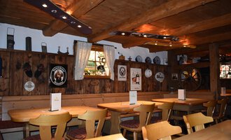 A cozy restaurant with wooden furniture and a rustic atmosphere. The walls are adorned with decorative plates and pictures. | © s‘Älpele | Marco Mitterer