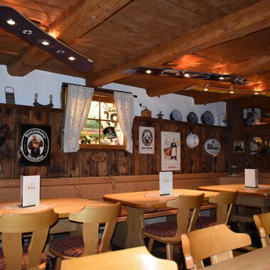 A cozy restaurant with wooden furniture and a rustic atmosphere. The walls are adorned with decorative plates and pictures. | © s‘Älpele | Marco Mitterer