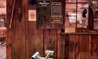 A rustic ambiance with wood interior and a log as a table. On the table lie two tools and various signs hang on the wall. | © s‘Älpele | Marco Mitterer