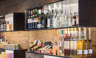 Shelves with various beverages, including wines, spirits, and liqueurs. Next to them, candies and snacks can also be seen. | © Kleinwalsertal Tourismus | Frank Drechsel