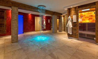 A modern wellness area with soft lighting effects. Wooden elements and sauna doors are located on the walls. | © Aparthotel Kleinwalsertal Haller GmbH & Co KG
