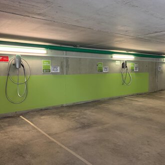 A modern underground parking garage with electric charging points. The walls are painted green and the lighting is bright. | © Naturhotel Chesa Valisa Hirschegg