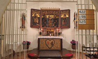 A protected altar space with a decorative altar shrine and candles. The wall is plain, and there are some flowers in the foreground. | © Unterwestegg-Kapelle Maria Hilf | Tanja Ritsch