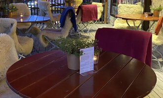 An inviting outdoor area of a restaurant with a round table and cozy chairs. The lighting and surroundings create a relaxed atmosphere in the evening. | © Uusziit | Chantal Kessler